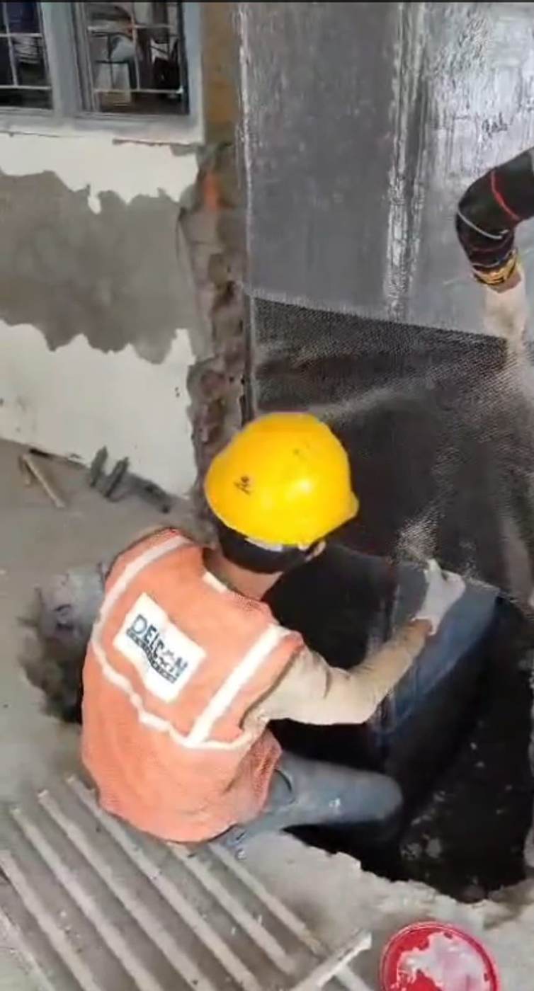 Site engineers applying carbon fiber mesh wrap to a column