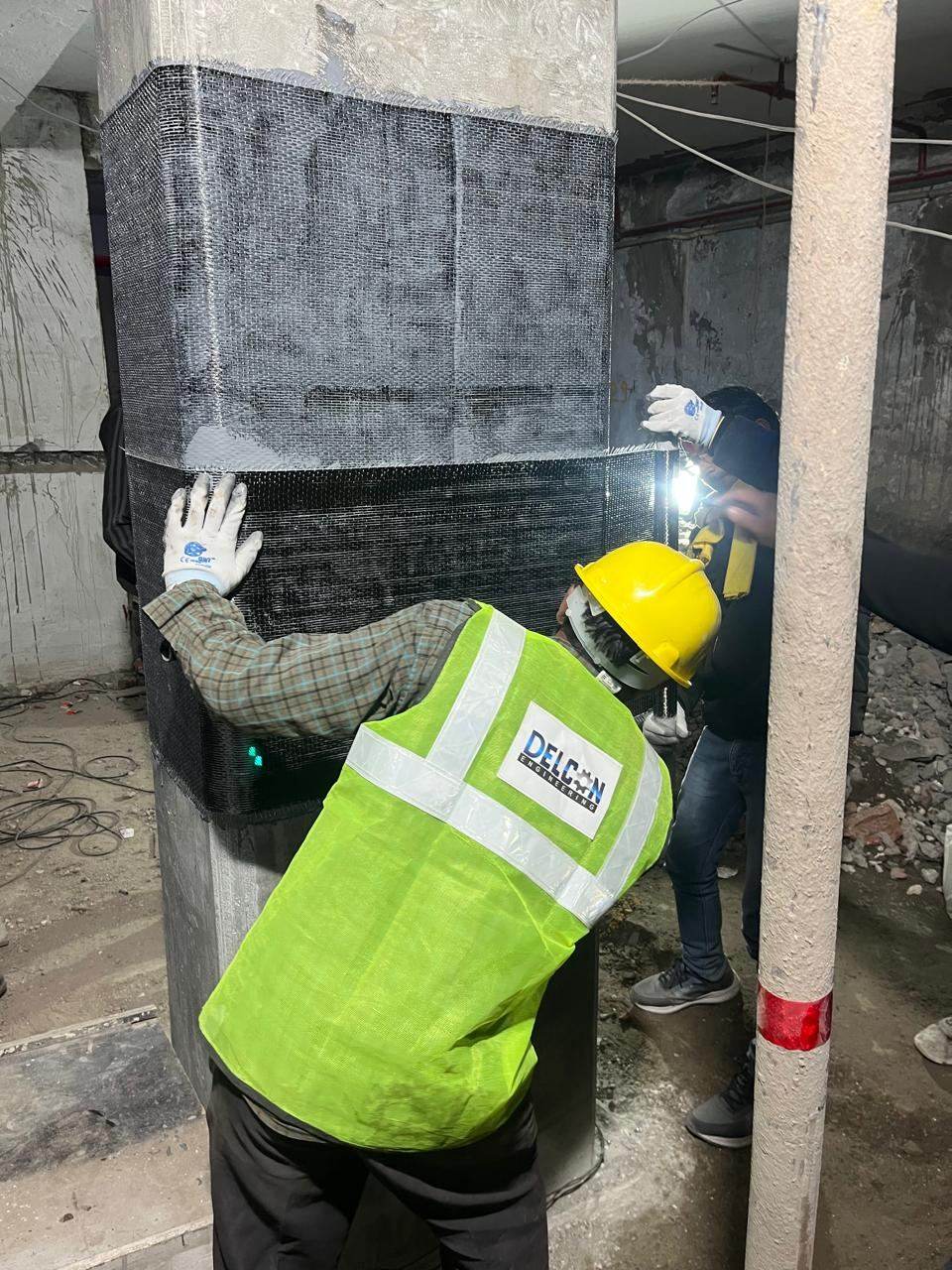 Worker applying carbon fiber wrap at a column base