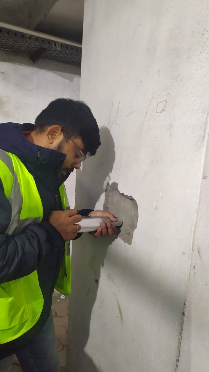 Engineer performing a rebound hammer NDT test on a concrete wall