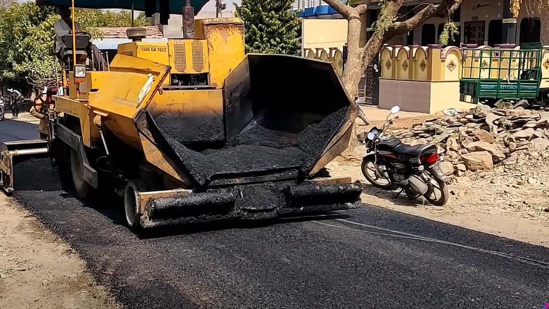 Paver machine dumping asphalt mix during road construction